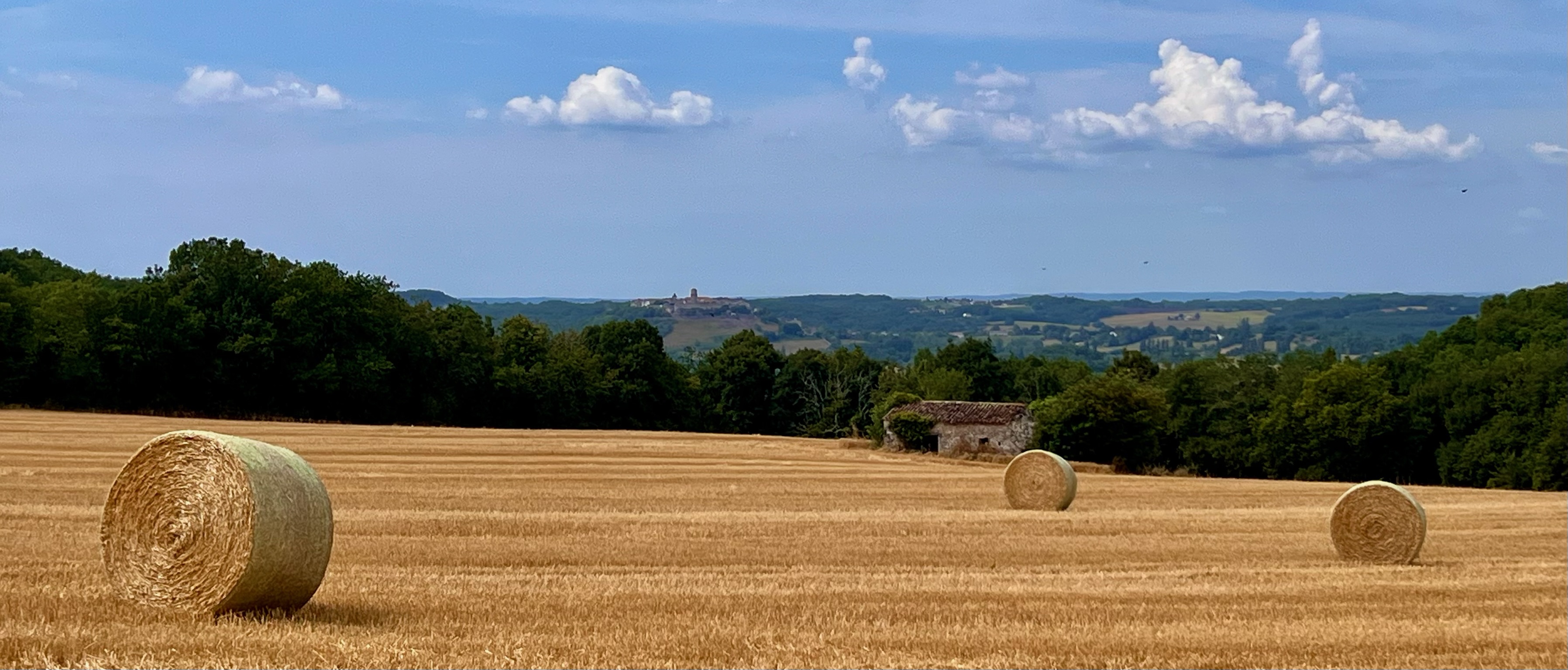 Bottes de paille et village perché dans la campagne du Quercy